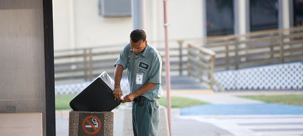 Photo of man emptying trash can.